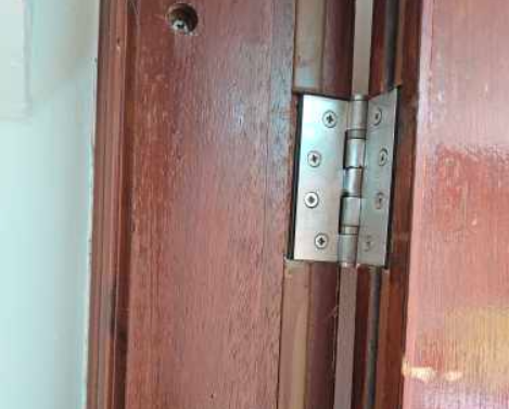 Fire door hinge showing missing intumescent seal and damage in a healthcare facility